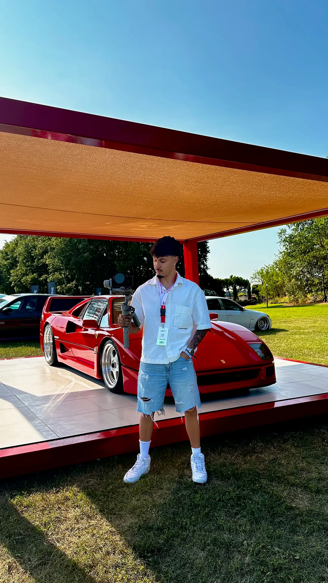 DG Visuals junto a un Ferrari F40 rojo en una exposición al aire libre