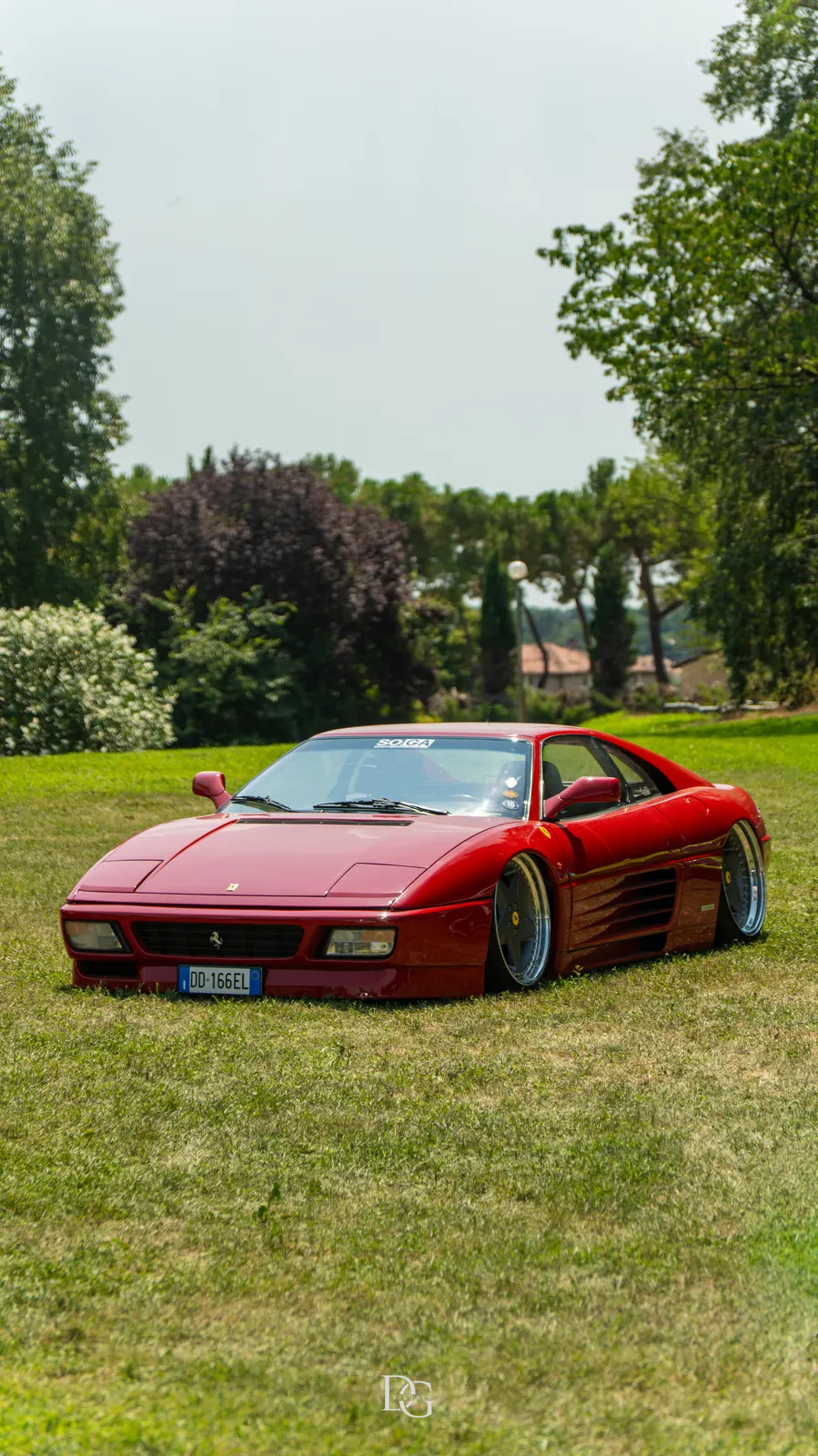 Ferrari rojo clásico junto a los árboles